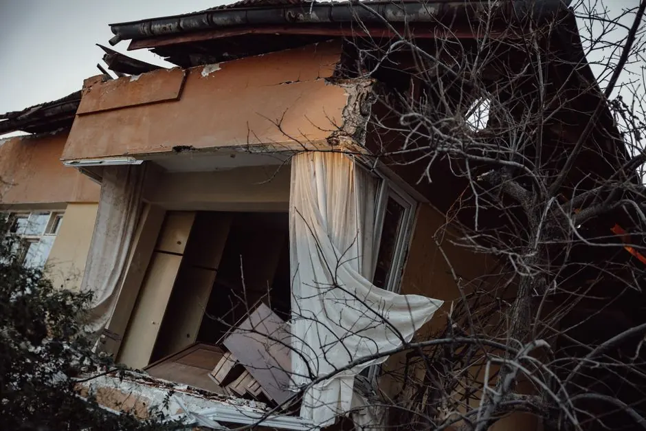 Exterior of a damaged house showing destruction from a natural disaster.